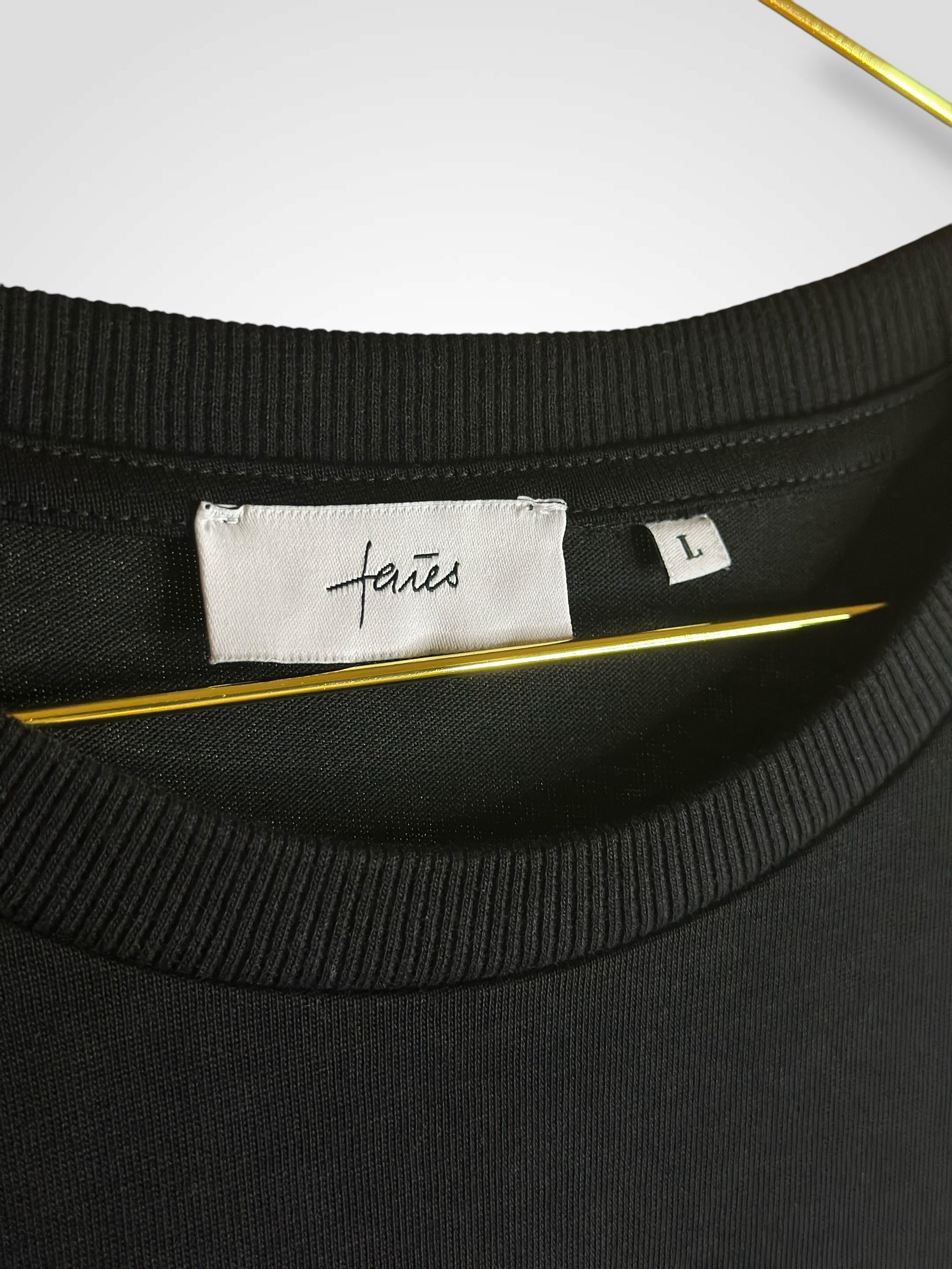 Schwarzes oversized T-Shirt mit weißem, abstrakten Gesichtslinien-Design auf dem Rücken und „faies“-Schriftzug – minimalistischer Streetwear-Stil auf schwarzem Hintergrund.