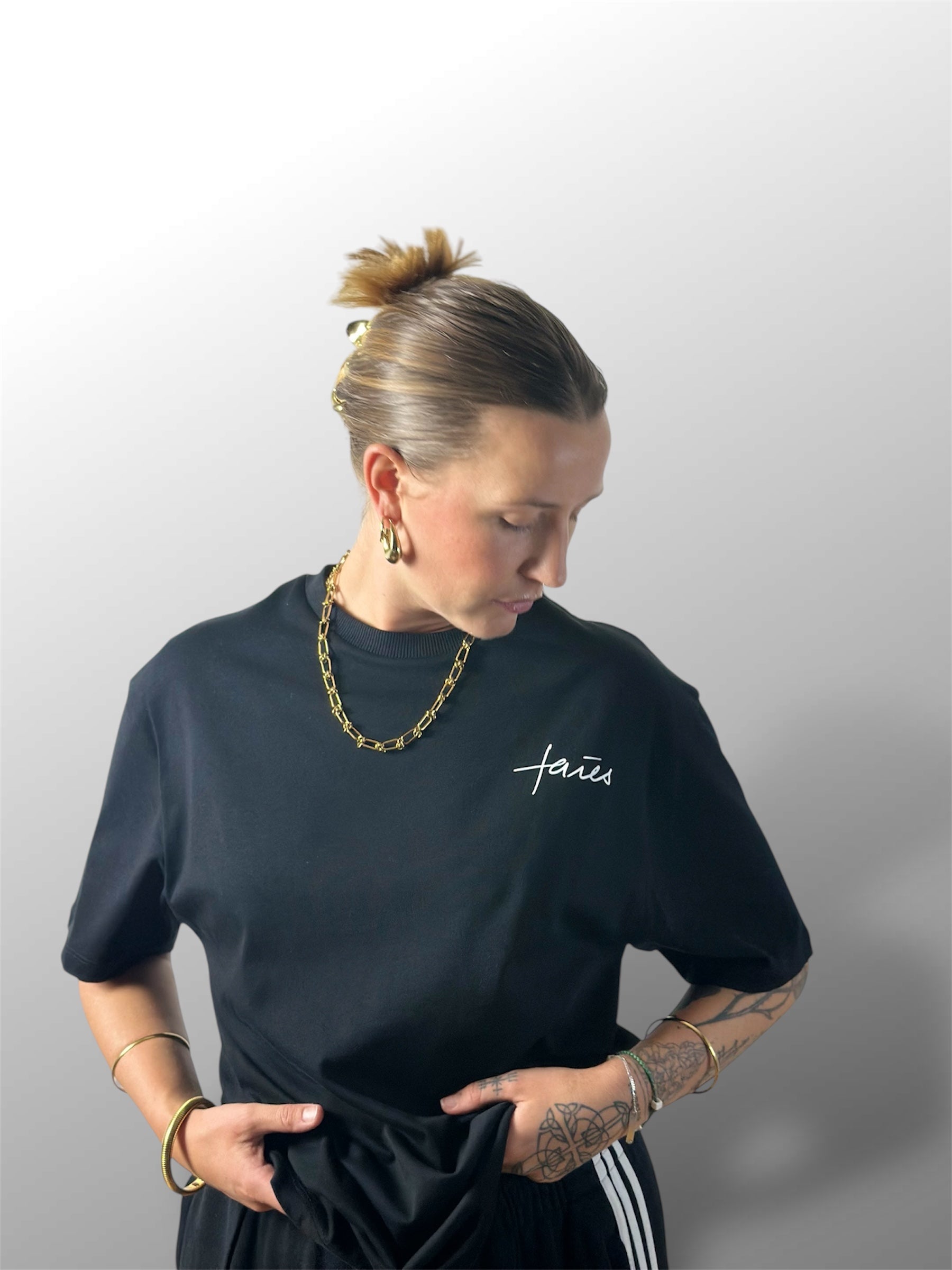 Schwarzes oversized T-Shirt mit weißem, abstrakten Gesichtslinien-Design auf dem Rücken und „faies“-Schriftzug – minimalistischer Streetwear-Stil auf schwarzem Hintergrund.